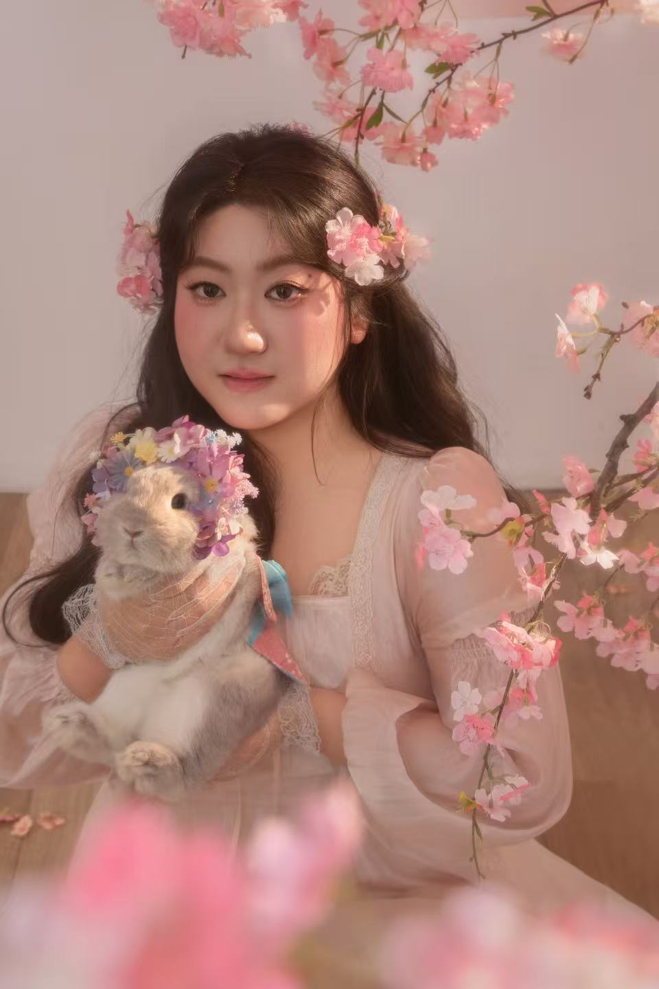 Chenhui Jia holding a rabbit, surrounded by pink blossoms